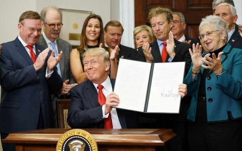 US President Donald Trump shows an executive order which he just signed on health insurance on October 12, 2017 in the Roosevelt Room of the White House in Washington, DC.