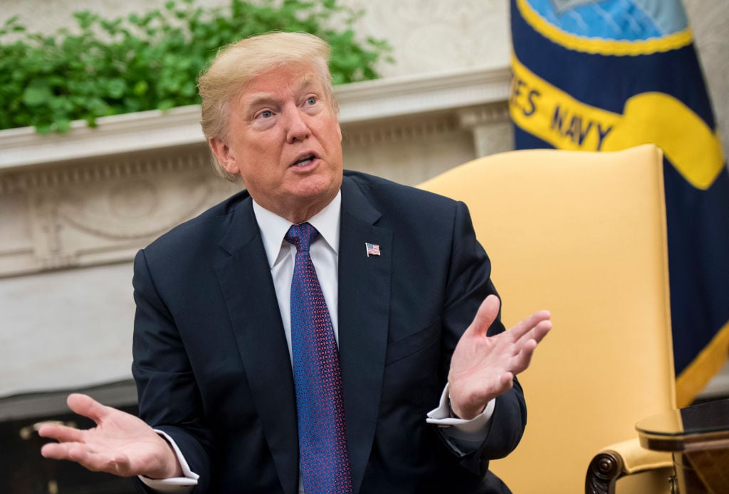trump in a dark suit on a tan chair with his hands up trump in a dark suit on a tan chair with his hands up