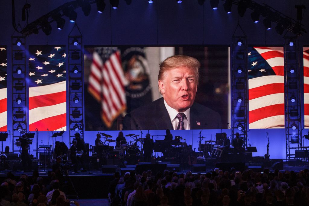 a television screen with Trump speaking backed by an American flag at the hurricane relief concert a television screen with Trump speaking backed by an American flag at the hurricane relief concert