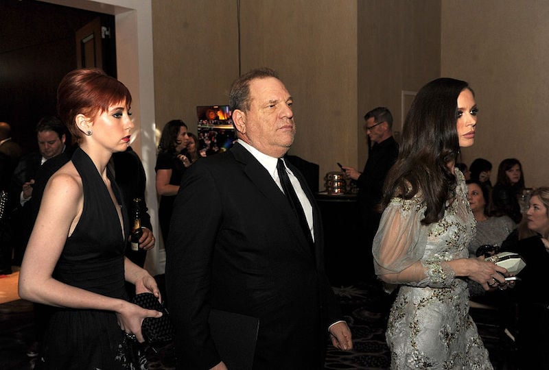 Harvey Weinstein stands in between two women