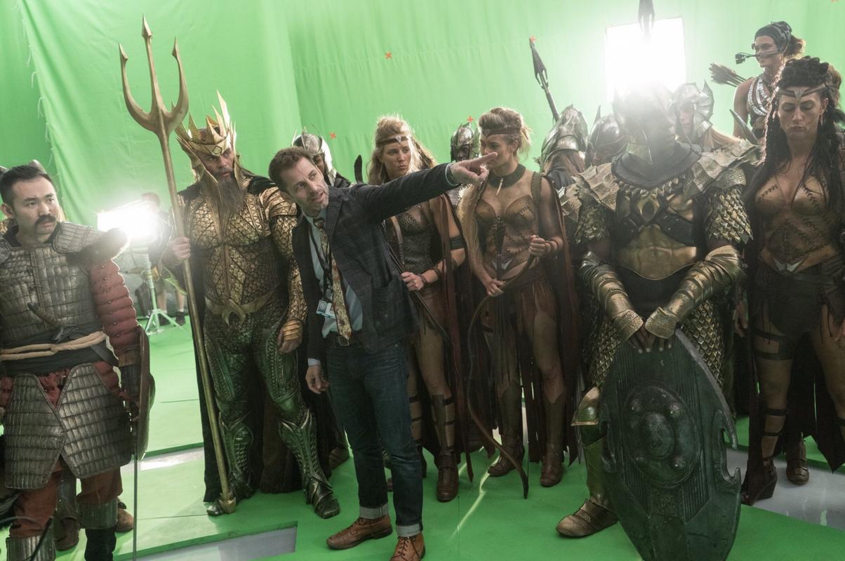 Zack Snyder points to something off=screen while standing in front of a group of actors on a green screen Zack Snyder points to something off=screen while standing in front of a group of actors on a green screen