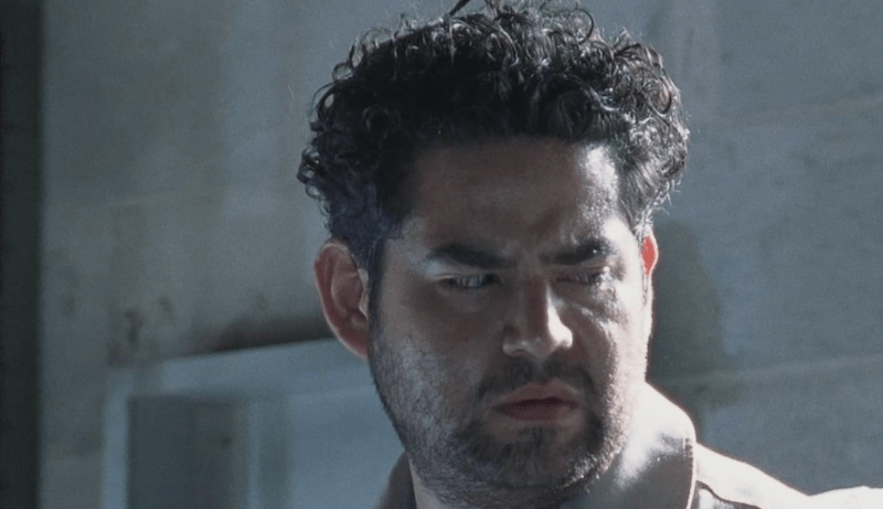 Morales looks downward while standing behind a white wall. Morales looks downward while standing behind a white wall.