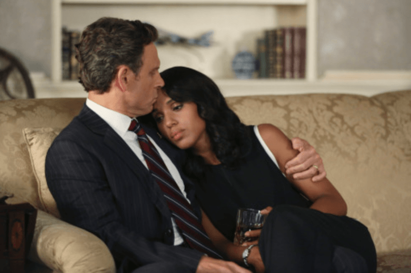 Olivia and Fitz sit on a couch together as he wraps his arm around her and she holds a glass.