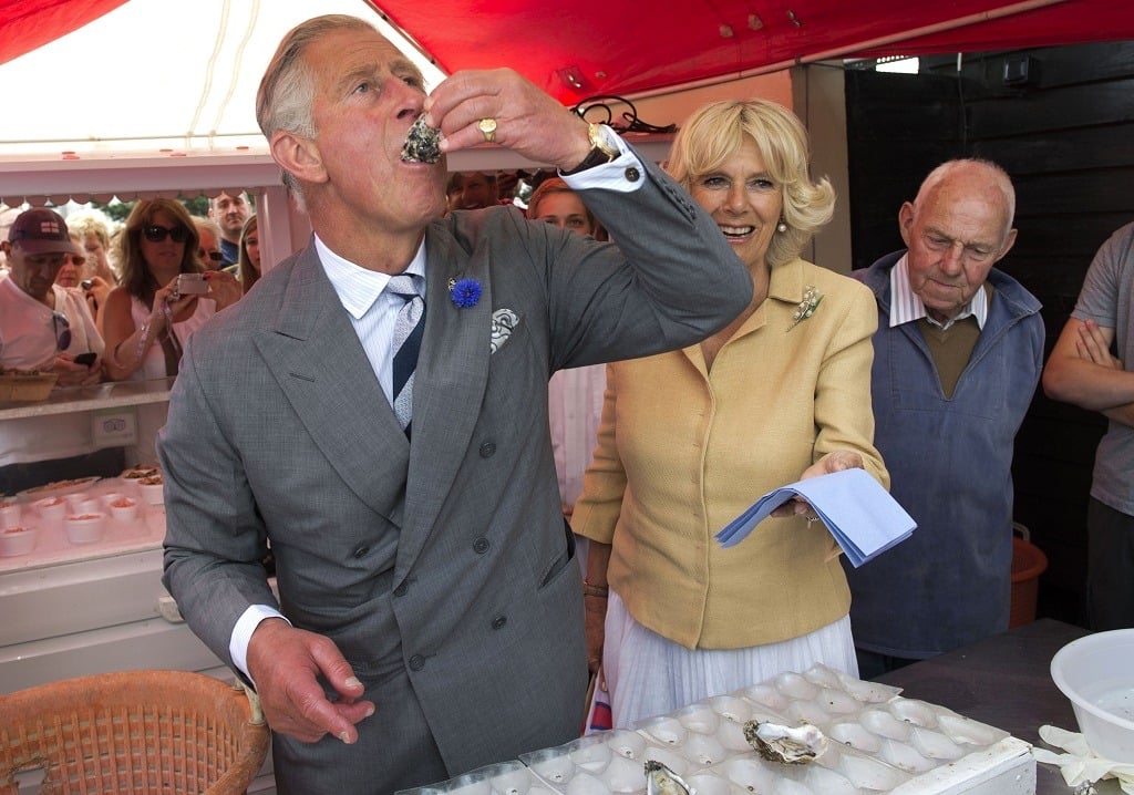 Prince Charles samples an oyster as Camilla, the Duchess of Cornwall, looks on.
