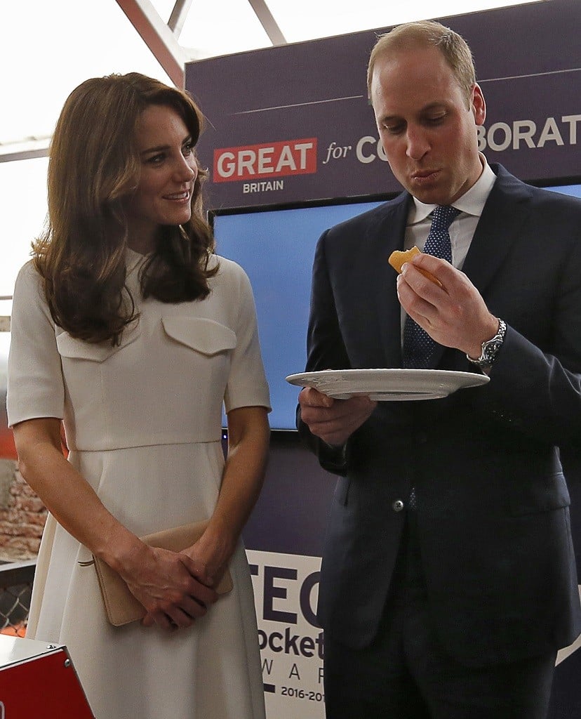 Prince William, Duke of Cambridge, eats traditional Indian food as his wife Catherine, Duchess of Cambridge looks on.