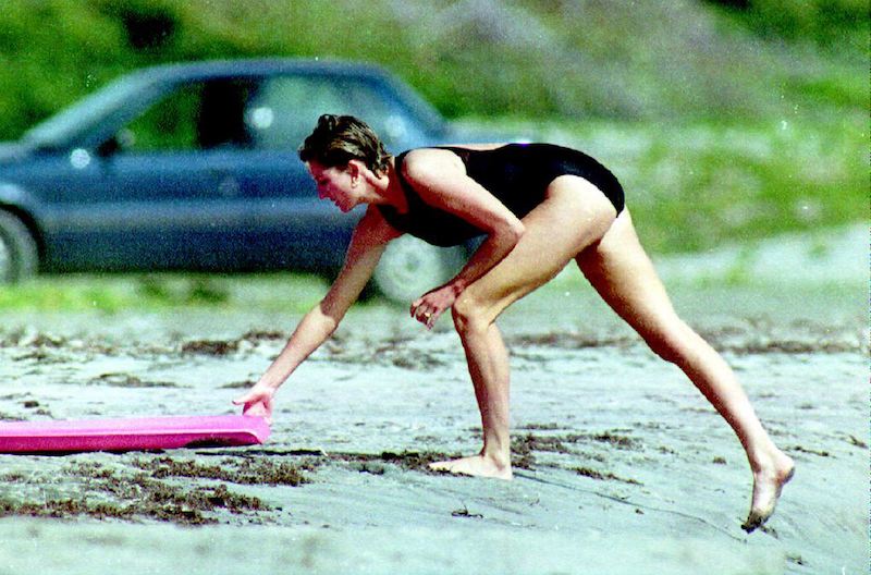 Princess Diana reaching for a surfboard.