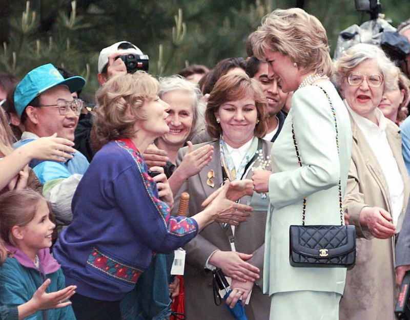 Princess Diana greets fans and shakes their hands. 