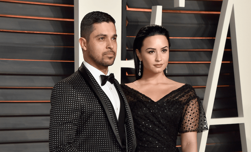 Demi stands next to Wilmer on a red carpet. 