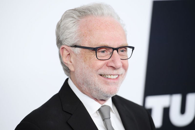 Wolf Blitzer smiles and poses for photographers while wearing a black suit and gray tie. Wolf Blitzer smiles and poses for photographers while wearing a black suit and gray tie.