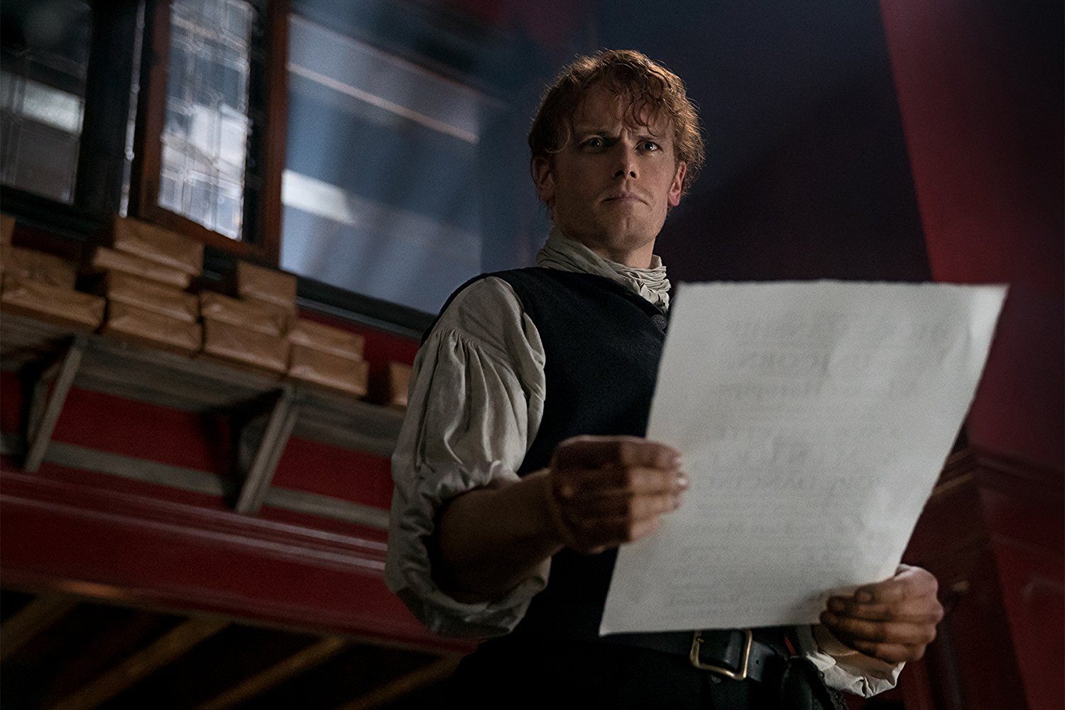 Jamie holding a piece of paper in Outlander