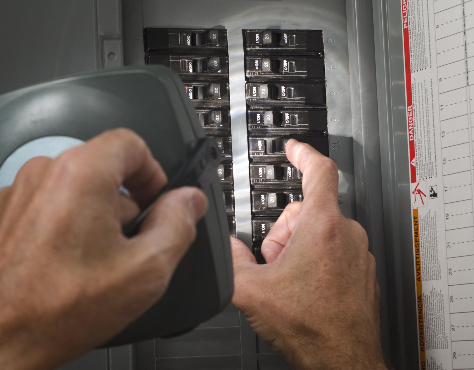 Man with flashlight looking at circuit breaker