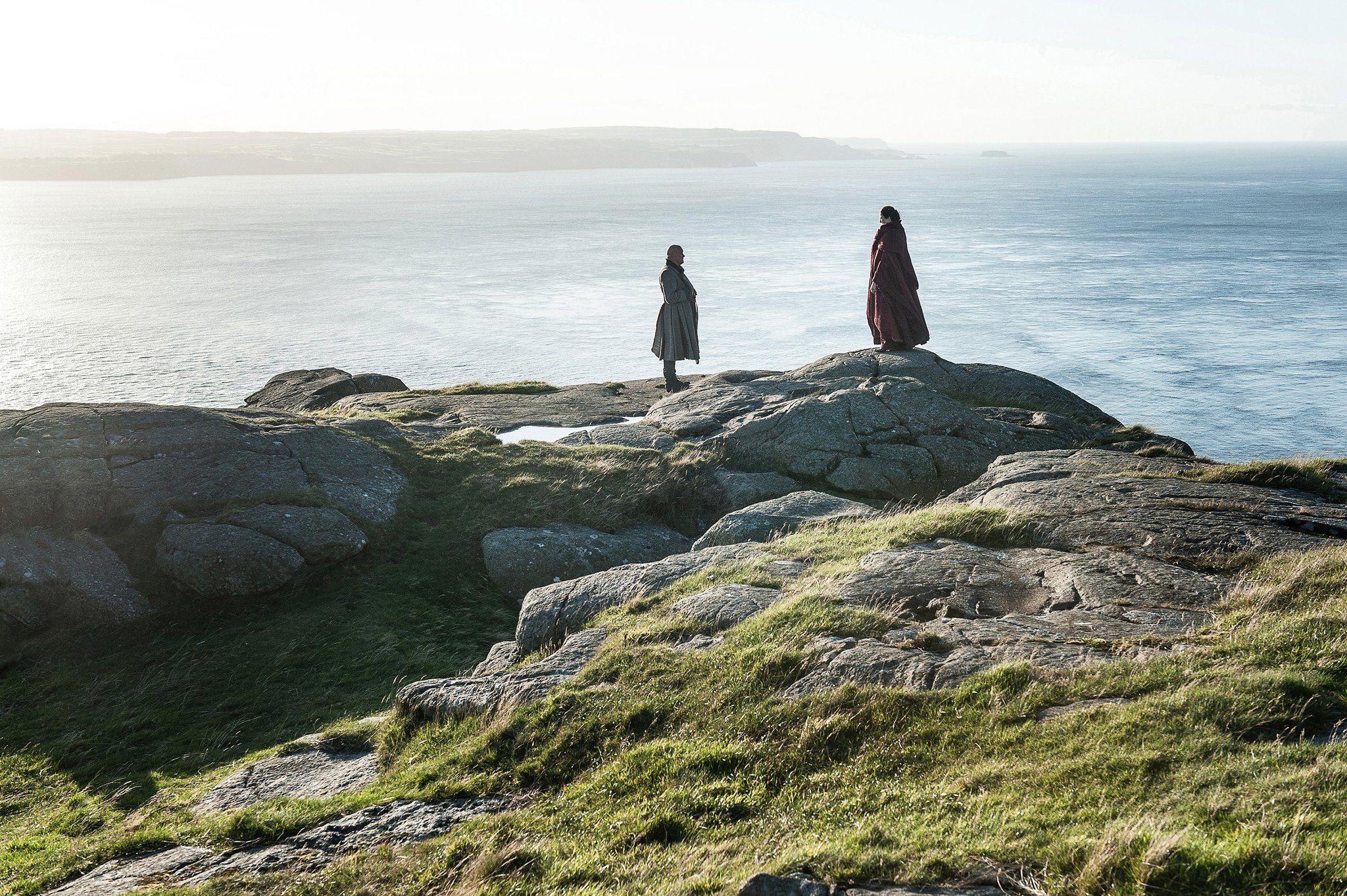 Varys and Melisandre speak on a cliff beside the ocean