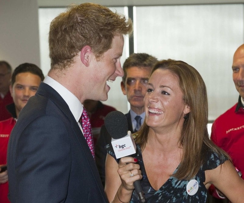 Natalie Pinkman holds up a microphone as Prince Harry speaks into it