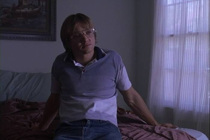 Jeremy Renner as Jeffrey Dahmer in Dahmer sitting on a bed