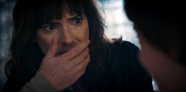 Joyce Byers holds a hand up to her mouth in Stranger Things 2 Joyce Byers holds a hand up to her mouth in Stranger Things 2