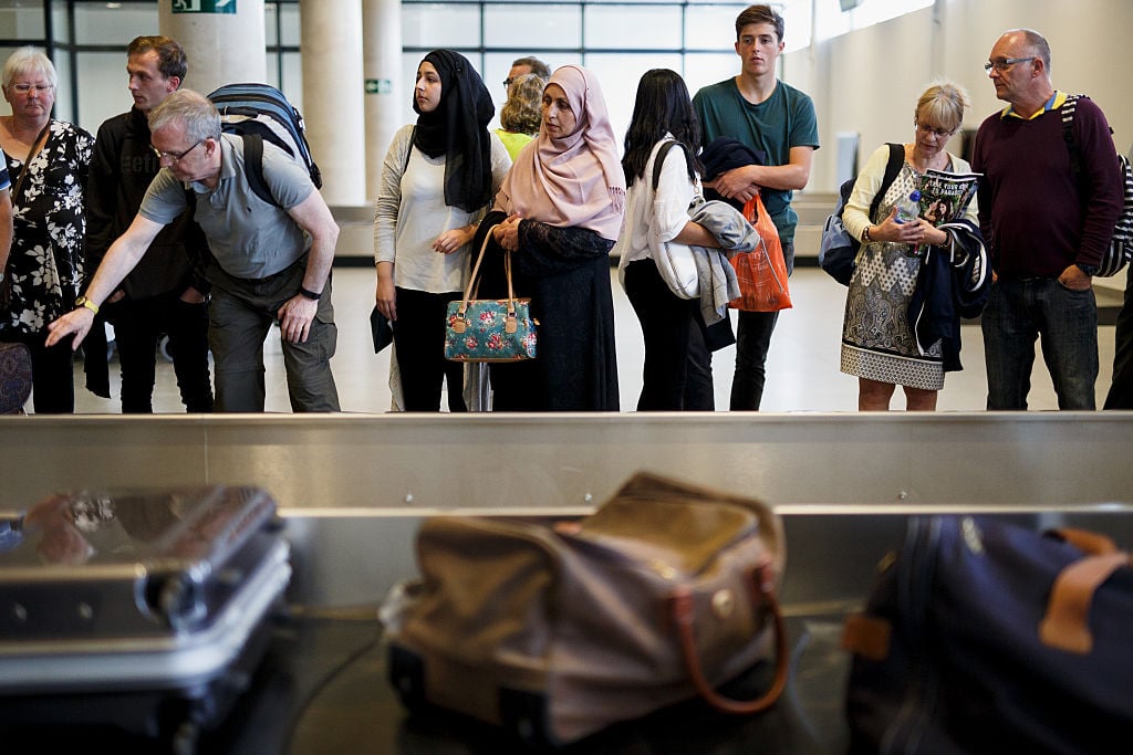 Passengers waiting for luggage at baggage claim.
