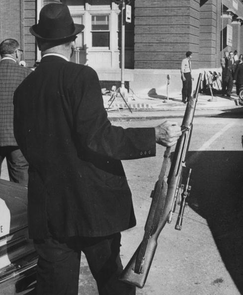 A man holding the rifle used by Lee Harvey Oswald in his assassination. A man holding the rifle used by Lee Harvey Oswald in his assassination.