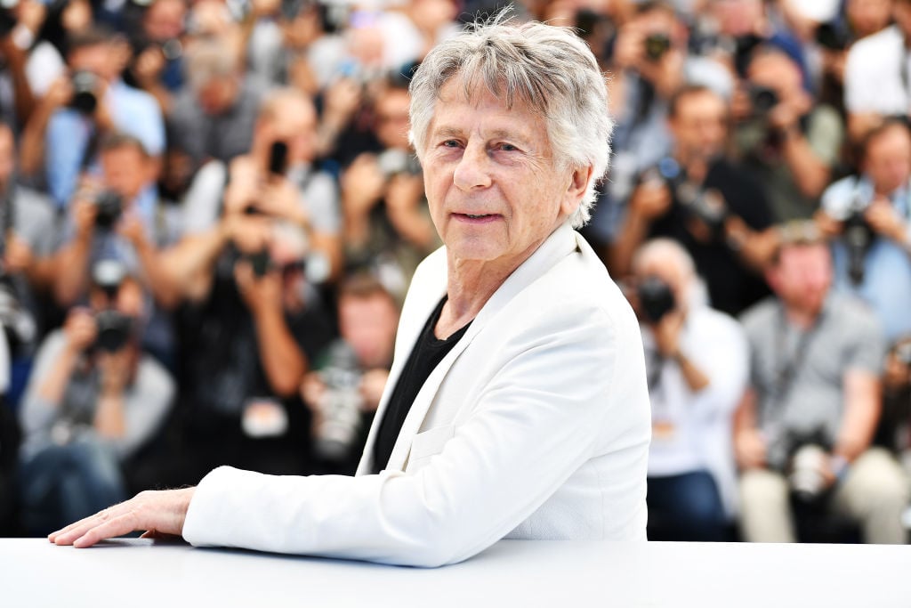 Roman Polanski standing in front of a group of photographers at the Cannes Film Festival.