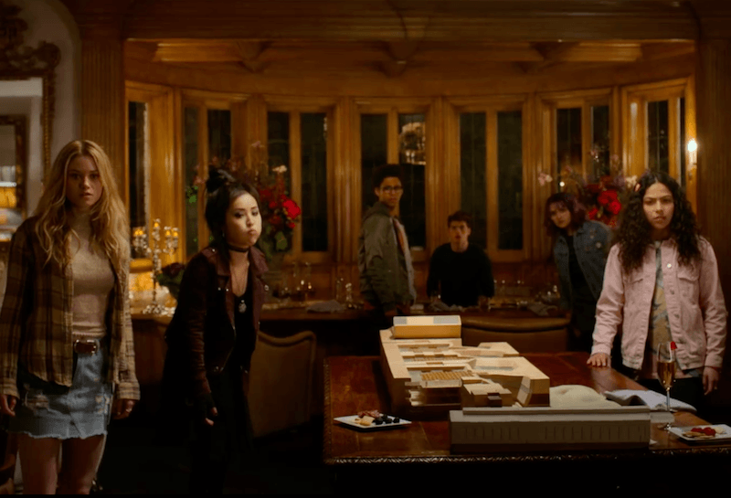 A group of teenagers stand around a table A group of teenagers stand around a table