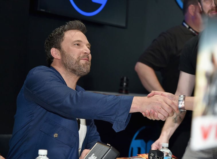 Ben Affleck in a blue jacket shaking someone's hand at Comic-Con. Ben Affleck in a blue jacket shaking someone's hand at Comic-Con.