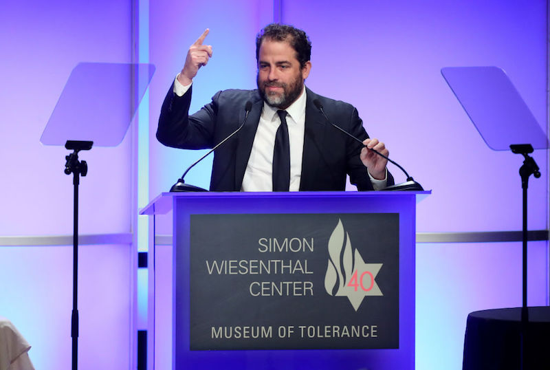 Brett Ratner speaks at a podium in front of a microphone. Brett Ratner speaks at a podium in front of a microphone.