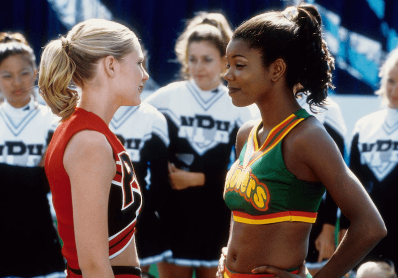 Two rival cheerleaders facing off in front of a crowd of performers. 