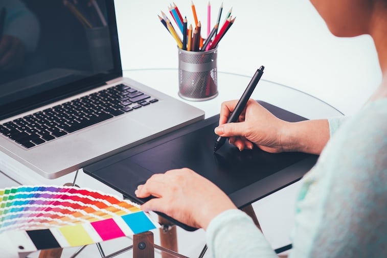Designer using graphics tablet and color charts