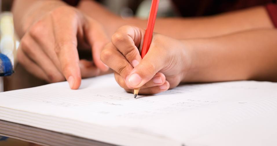 Dad helping elementary age daughter with school homework. Concept of parent spending time with family. Close-up of exercise book, pencil, hand writing on paper. Dad helping elementary age daughter with school homework