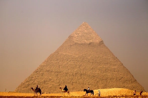 camels ride past the great pyramid