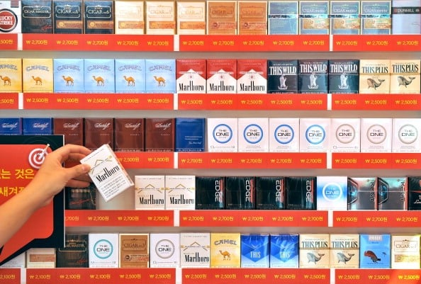 A campaigner holds a pack of cigarettes in front of a stand of tobacco boxes