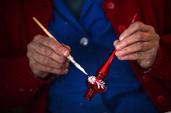 A woman paints a Christmas tree bauble in a small workshop.