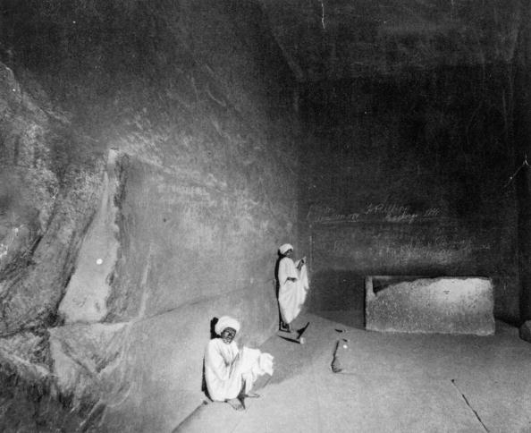 a black and white photo of archaeologists inside the great pyramid