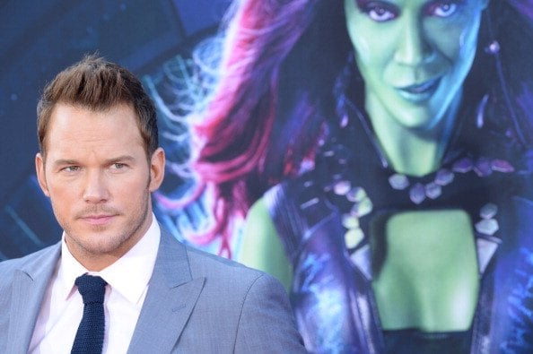 chris pratt in front of a guardians of the galaxy poster