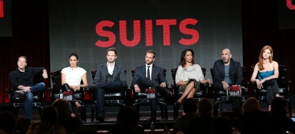 the cast of suits under a sign in red the cast of suits under a sign in red