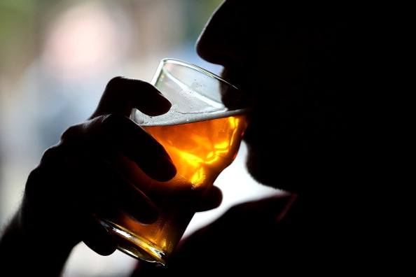a silhouette of a man drinking a beer