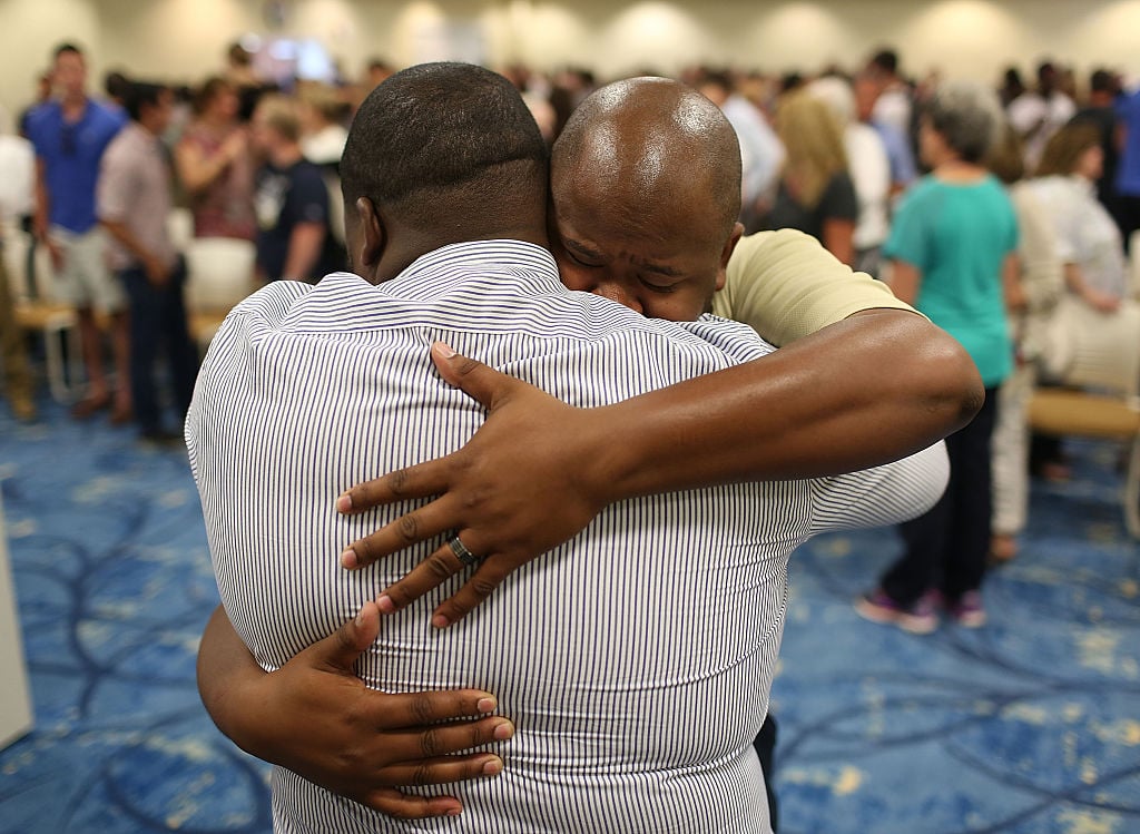 two men embrace with a crowd behind them two men embrace with a crowd behind them