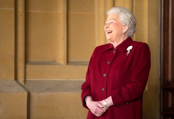 queen elizabeth in a burgundy suit laughing