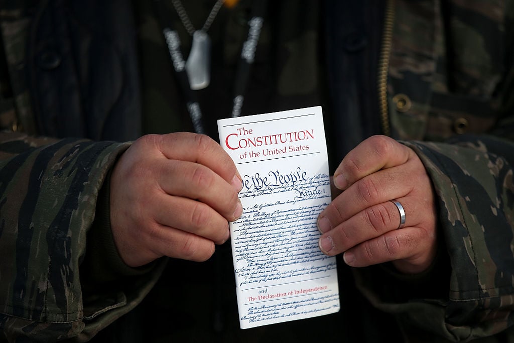 Hands of a normal sized person holds a small copy of the U.S. constitution. Hands of a normal sized person holds a small copy of the U.S. constitution.