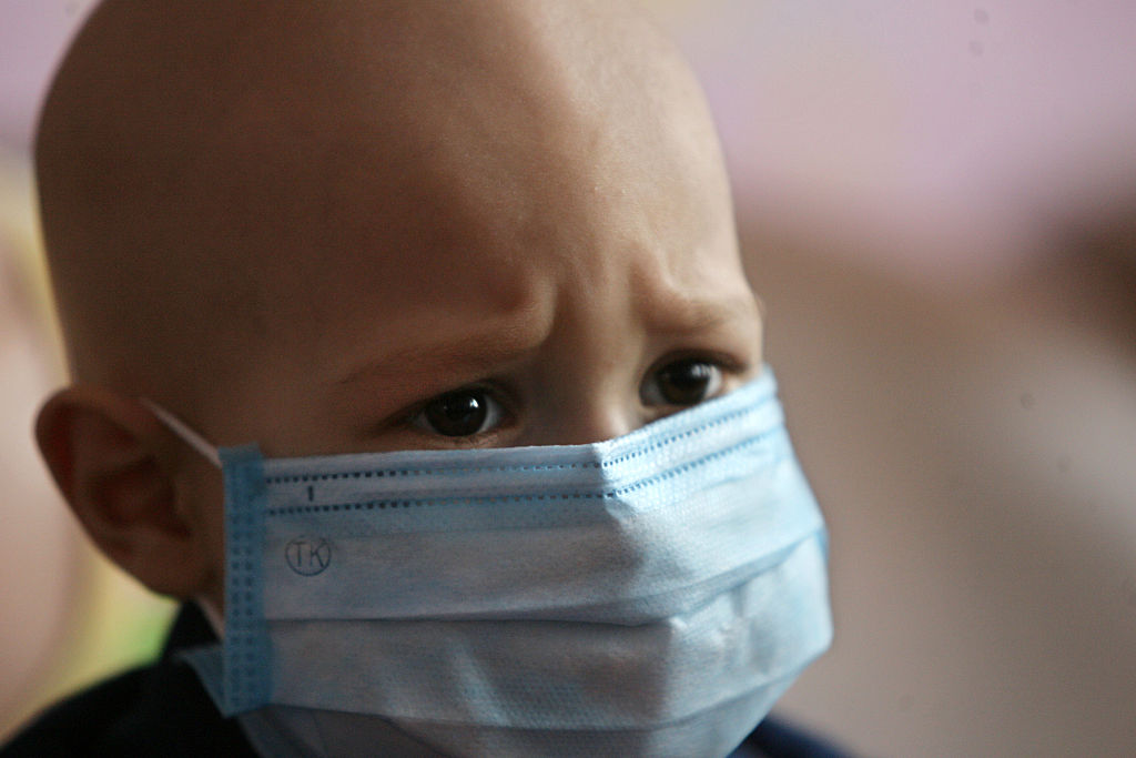 A child with cancer and a mask over his mouth and nose.