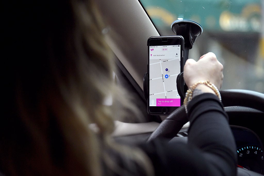 What is Lyft Personal Plan A Lyft driver operates a hands-free device holding a phone displaying a map in the drivers side of a vehicle.