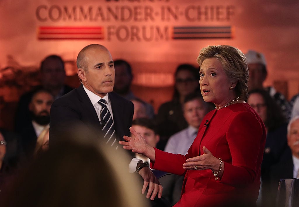 Matt Lauer in a dark suit with Hillary Clinton in red Matt Lauer in a dark suit with Hillary Clinton in red