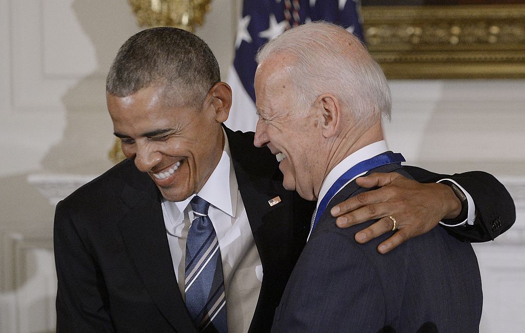 Barack Obama and Joe Biden share a laugh, both in suits