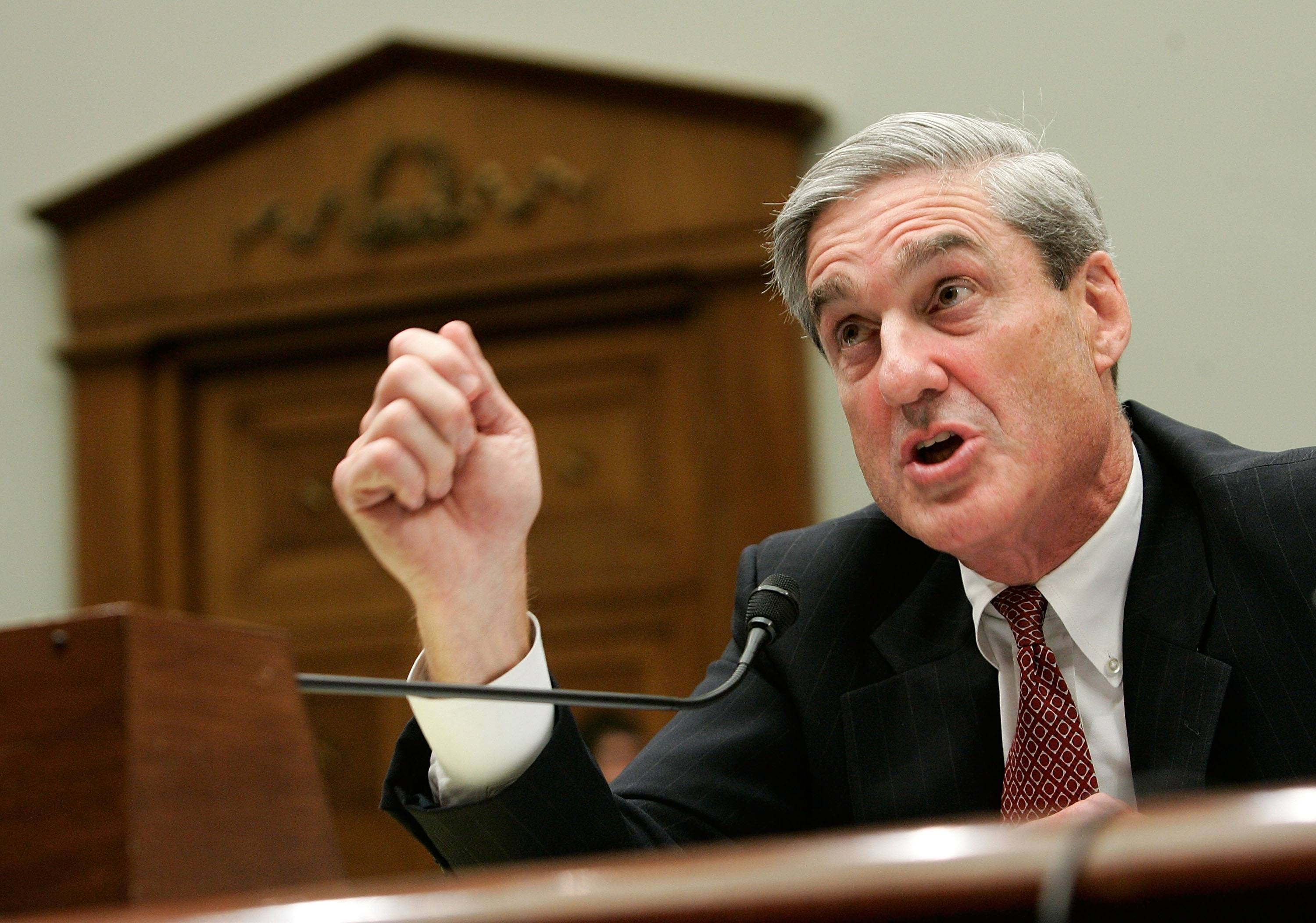 Mueller in a black suit screaming into a microphone. Mueller in a black suit screaming into a microphone.