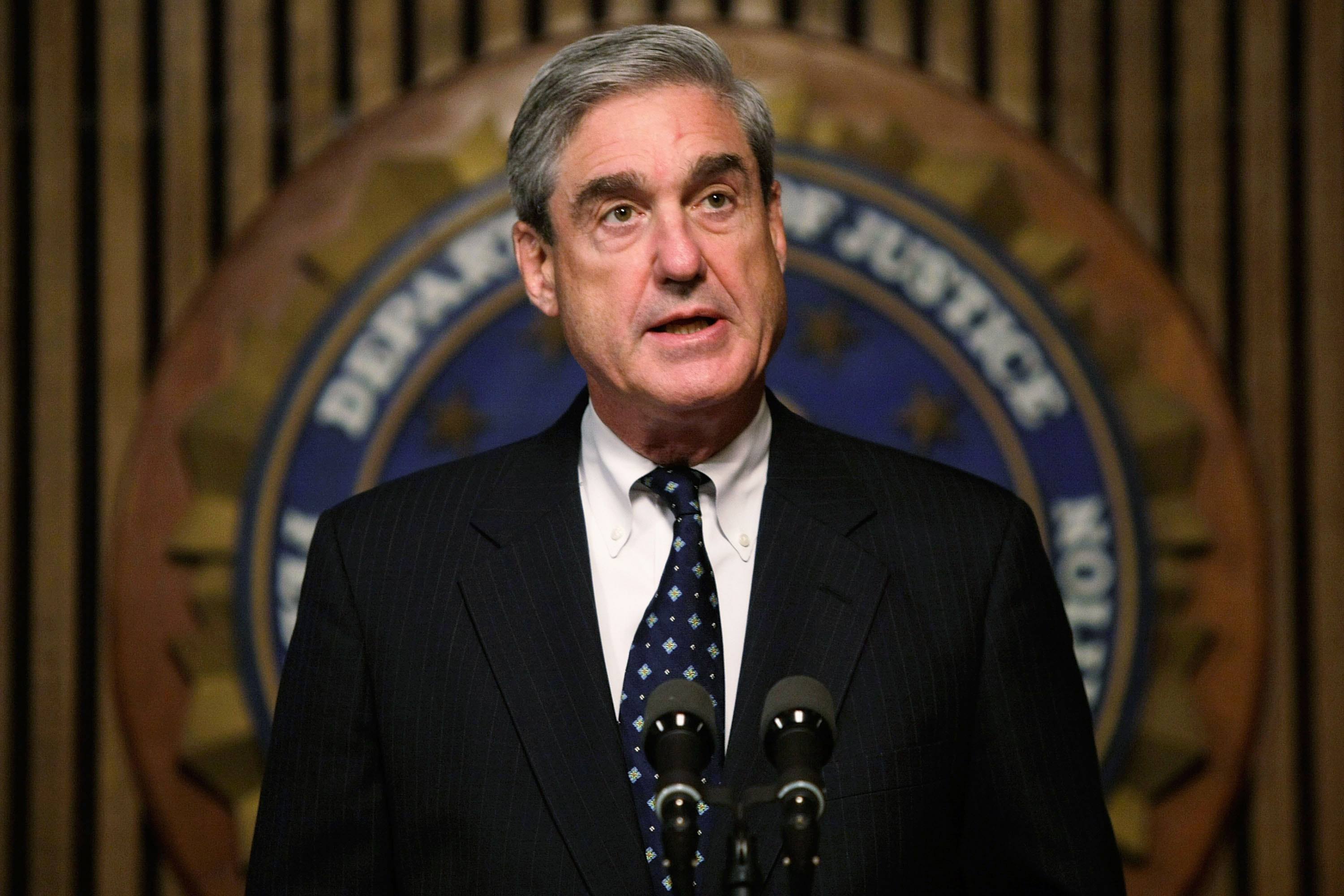 Mueller standing in front of the seal of The DOJ.