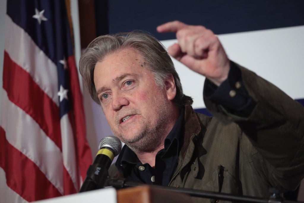 steve bannon shouting in a dark shirt with an american flag