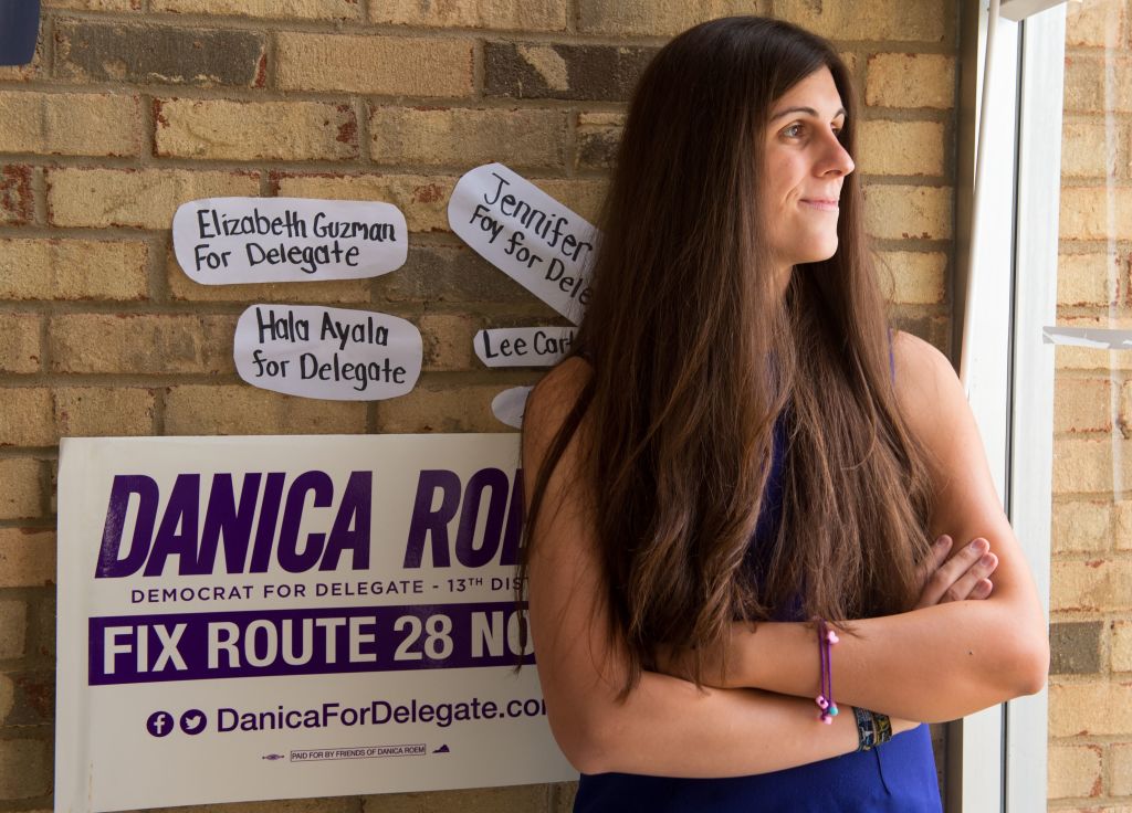 danica roem in blue against a brick wall, looking out the window