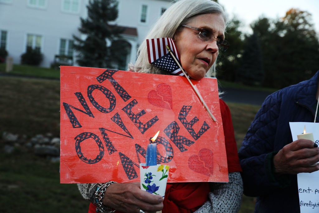 a woman holds a red sign and an American flag in a vigil against gun violence in newtown connecticut a woman holds a red sign and an American flag in a vigil against gun violence in newtown connecticut