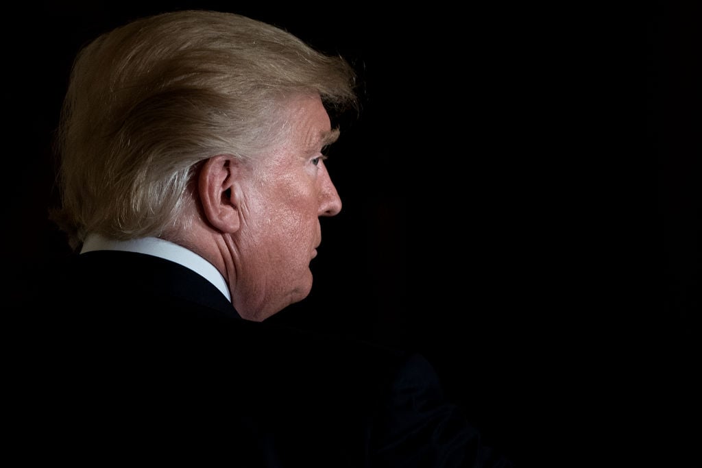 trump from the back on the left, tight on his head against a black background