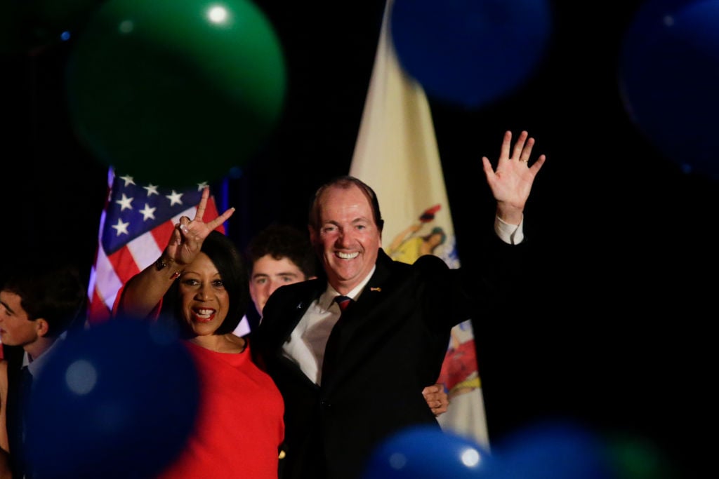 Phil Murphy celebrates his victory ina black suit while waiving at the crowd.