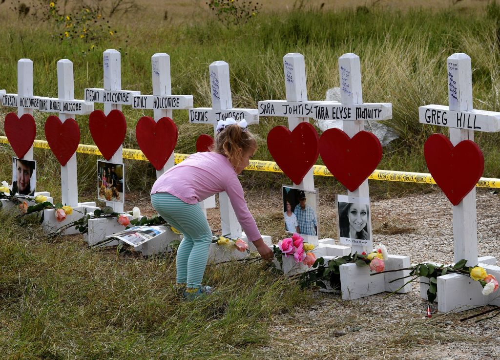 a child in a pink shirt leaves flowers next to a line of crosses with red hearts a child in a pink shirt leaves flowers next to a line of crosses with red hearts
